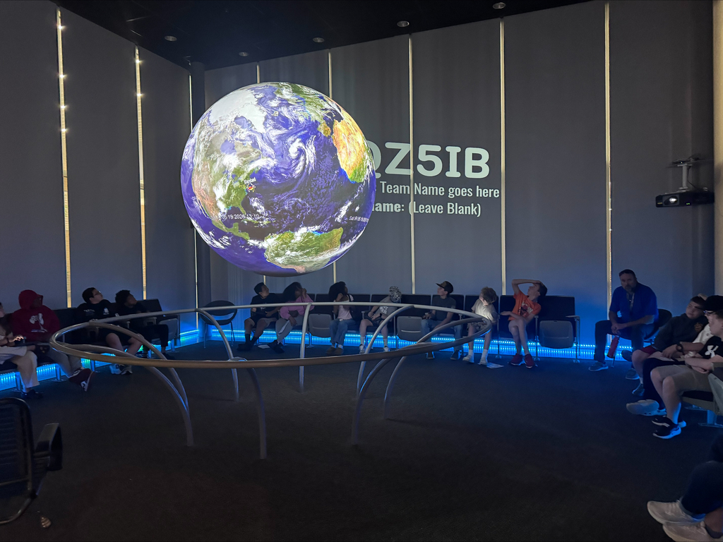 students  sitting around a large sphere with the earth projected on it
