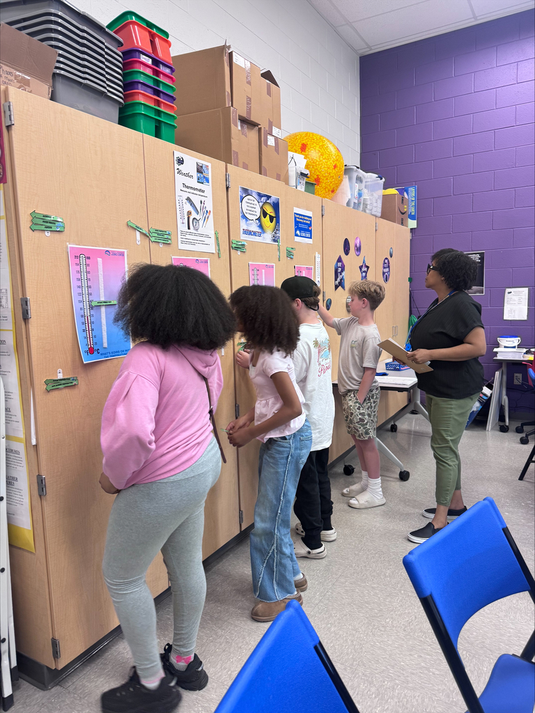 students standing and looking at charts posted on science classroom cabinets