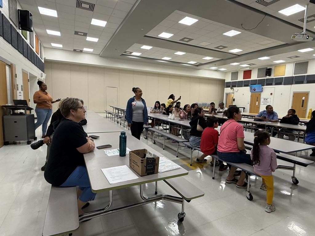     Students and families participate in an interactive middle school presentation and raise their hands to answer questions during the event.