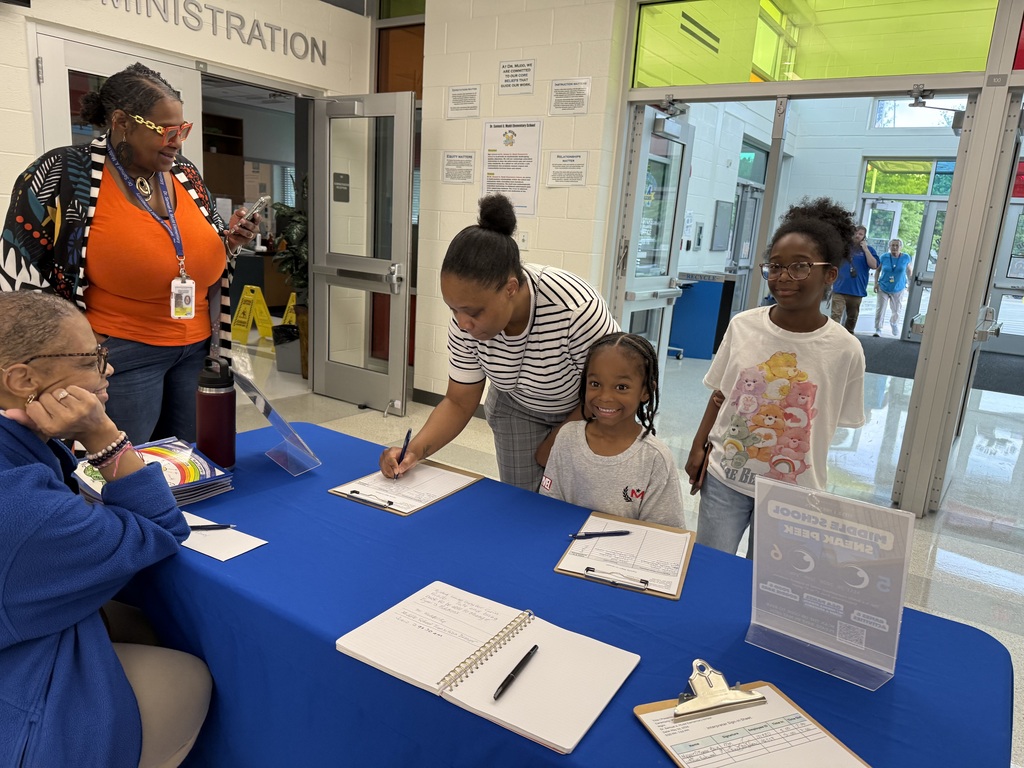     Families and students check in at the welcome table during the Middle School Sneak Peek event at Dr. Samuel A. Mudd Elementary School.