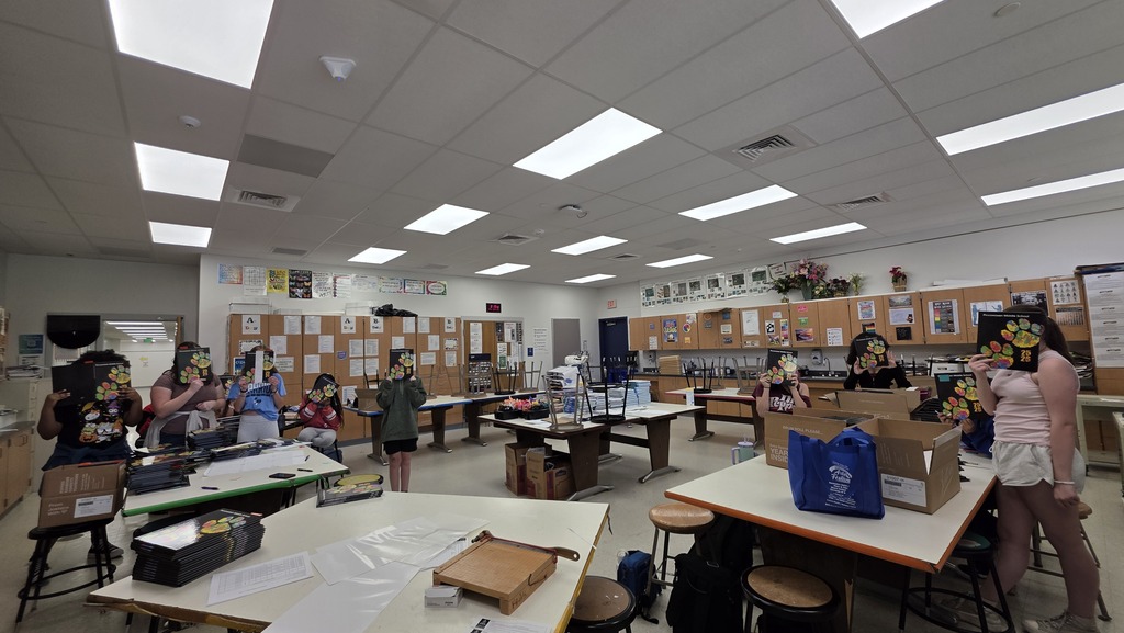 art classroom  with students holding yearbooks in front of their faces