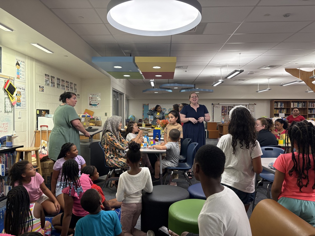 Families and students gather in the Dr. Mudd Elementary media center during 2nd Grade Transition Night. Third grade teachers speak with families and provide information about classroom expectations, academic programs, and the transition from 2nd to 3rd grade. Students sit and listen while families engage in discussions and ask questions about the upcoming school year. 