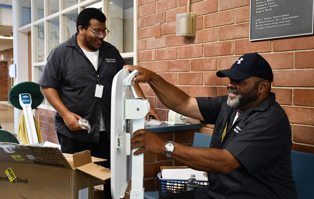 Two building service workers putting together a table