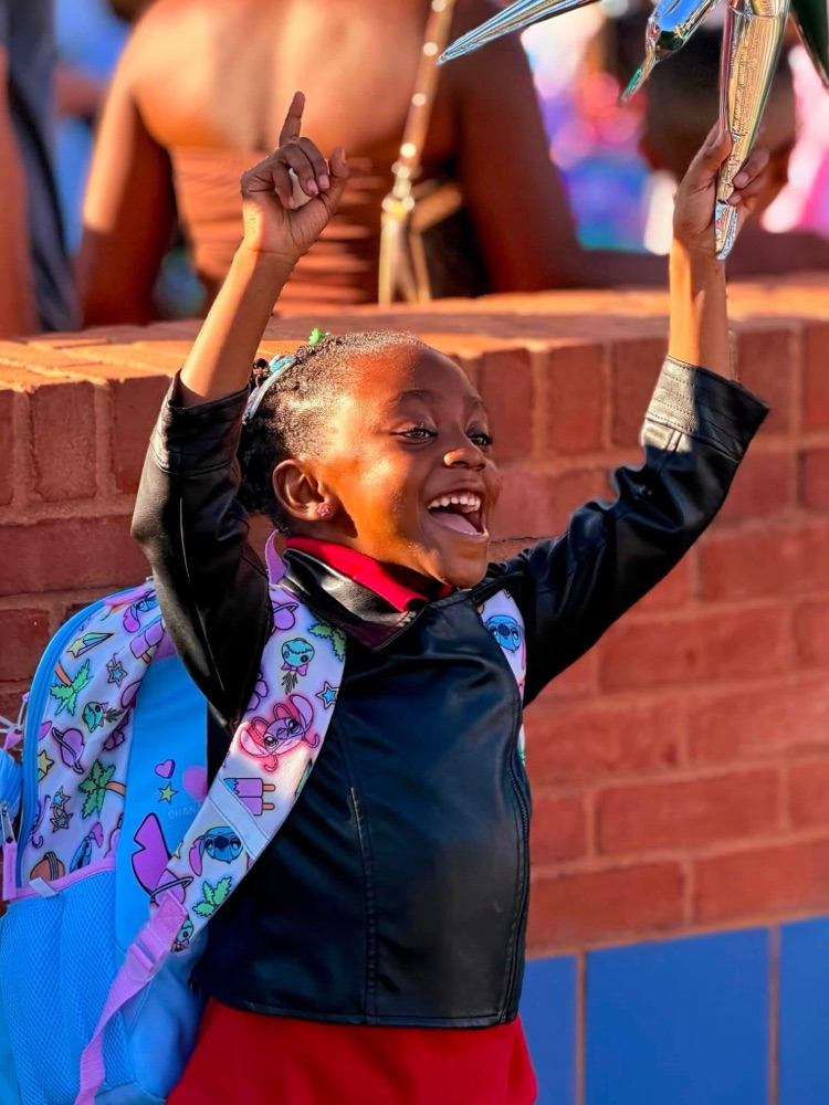 student with arms in the air smiling 