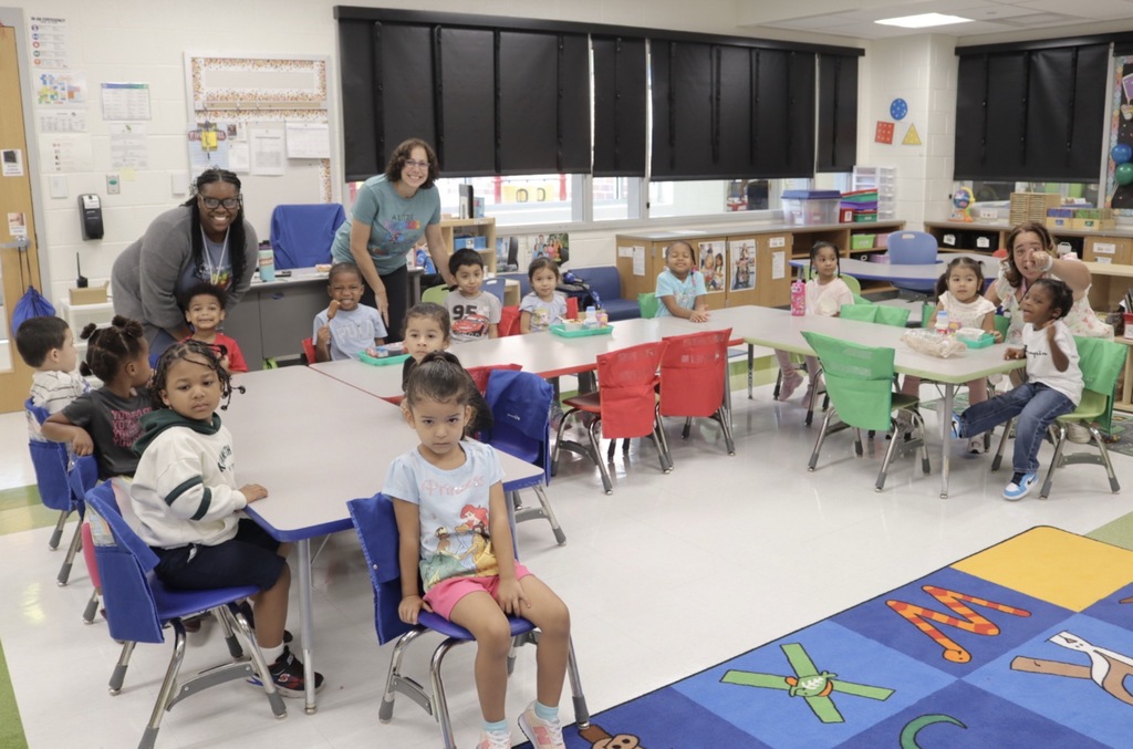 Pre-K students and teachers smile together in the classroom during the first day of school.