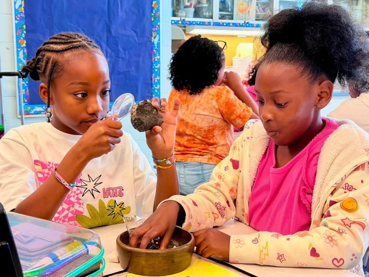 students looking at rocks with magnifying glass