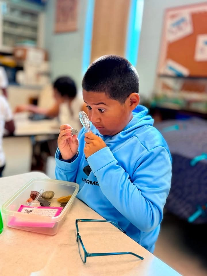 students looking at rocks with magnifying glass
