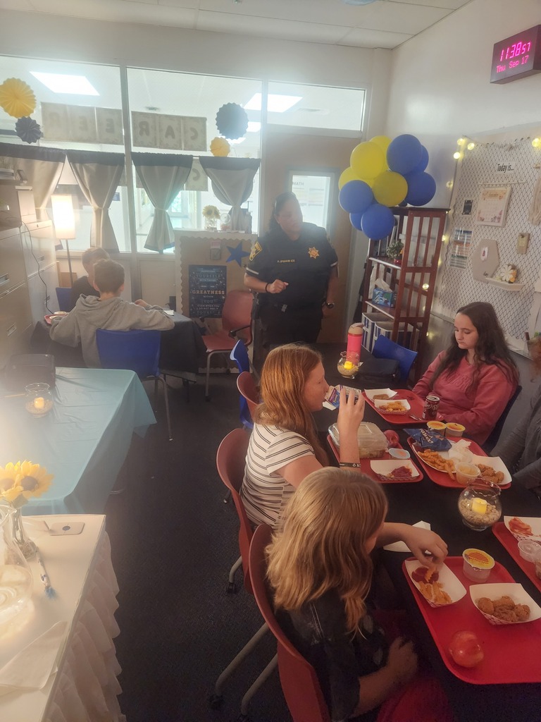 a picture of the school officer talking to a different group of students eating lunch