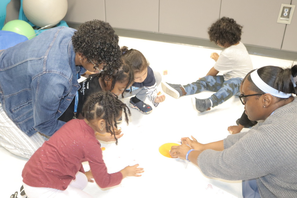 Pre-K students and teachers participate in a hands-on activity while learning about rainbow colors.