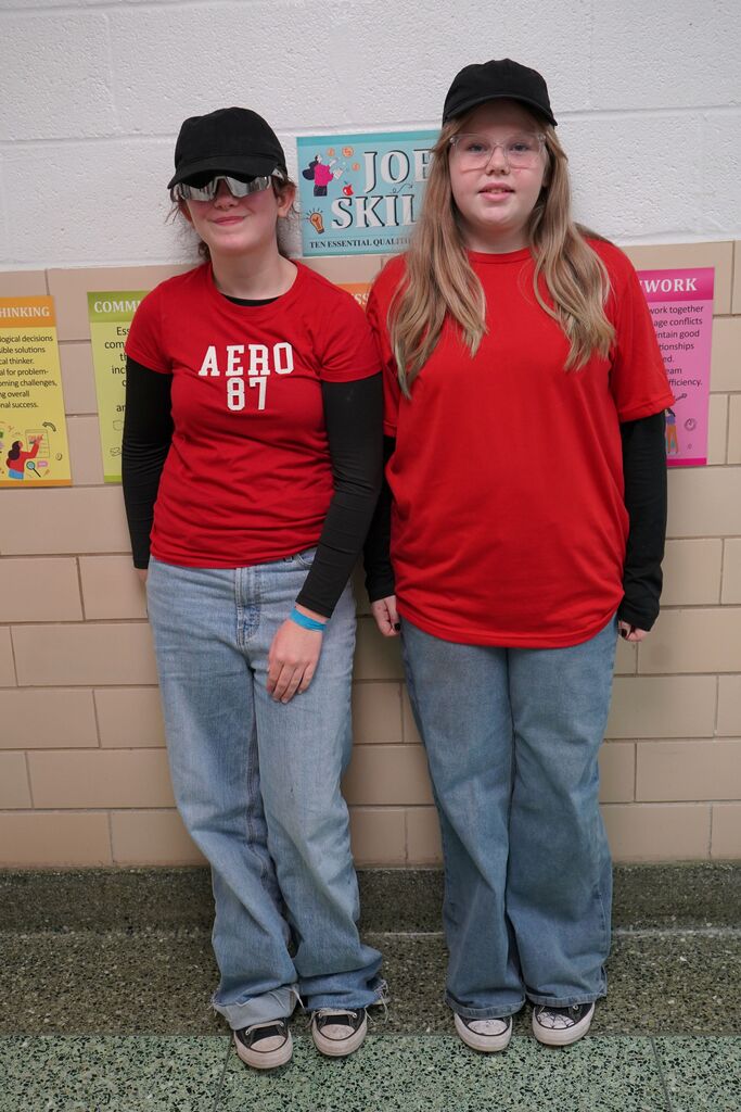 Two students wearing matching hats, red shirts, and blue jeans for Twin Day.