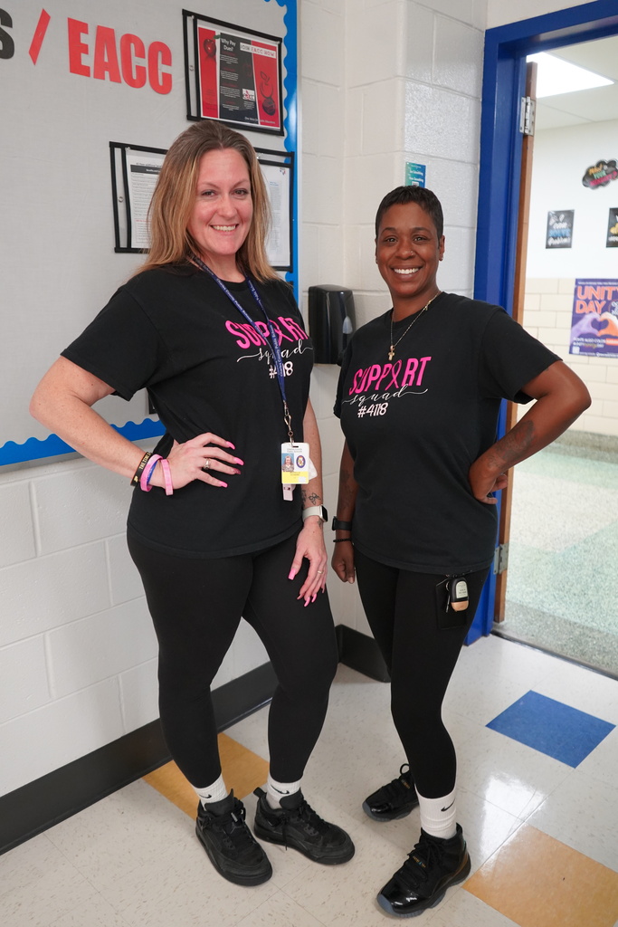 Two teachers wearing matching black T-shirts and leggings.