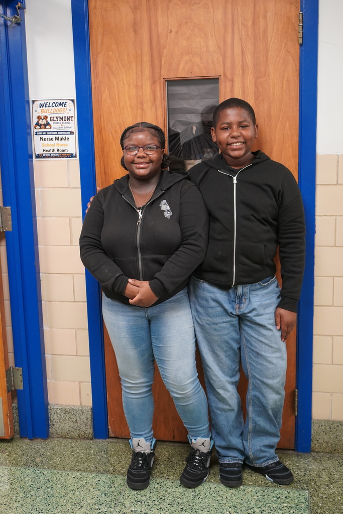 Two students, one girl and one boy, wearing black jackets and blue jeans.