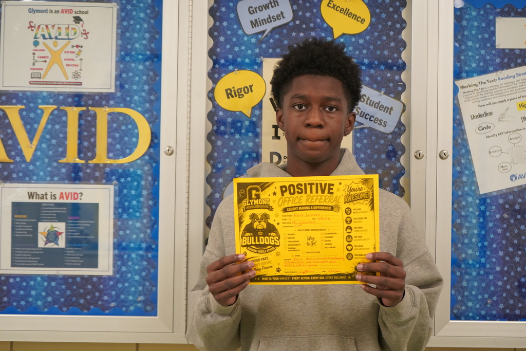 Boy standing holding a positive office referral award.