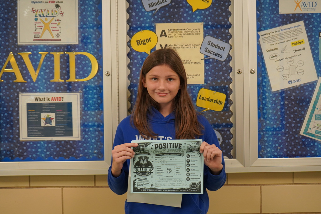 Girl standing holding a positive office referral award.