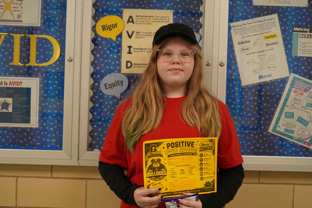 Girl standing holding a positive office referral award.
