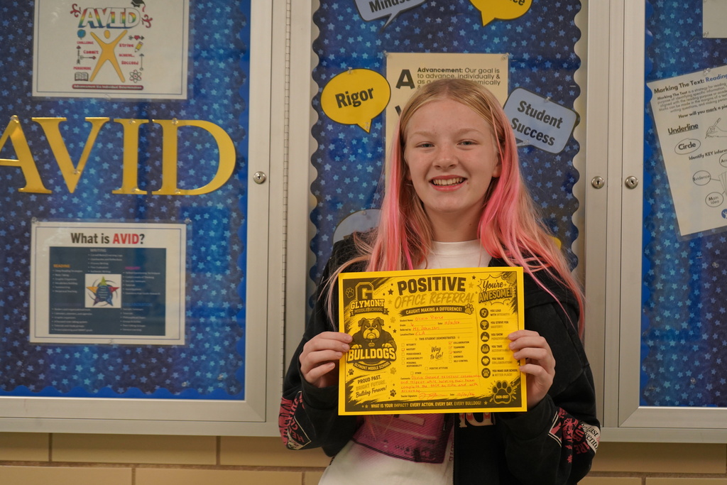 Girl standing holding a positive office referral award.