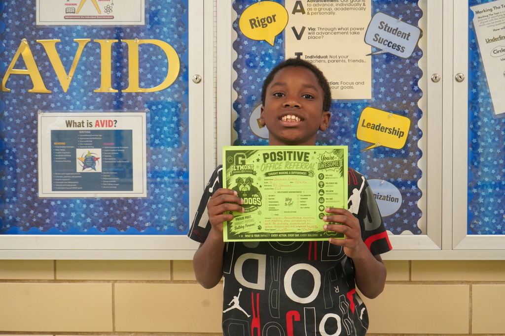 Boy standing holding a positive office referral award.