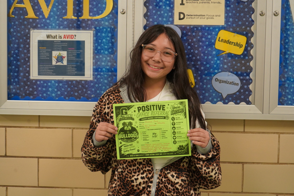 Girl standing holding a positive office referral award.