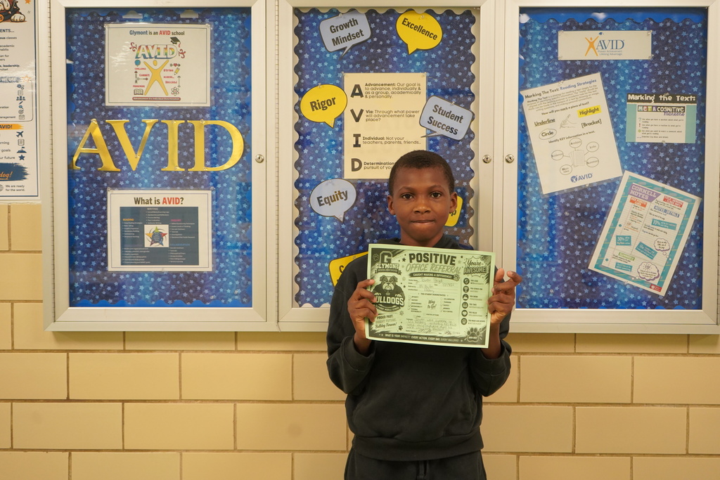 Boy standing holding a positive office referral award.