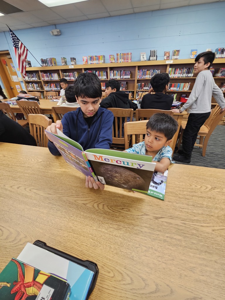 A kindergartener and a 7th grader read read a picture book together