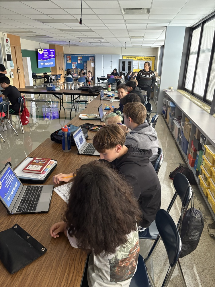 Second and Eighth graders meet with their buddies in the Steam Room planning their themes for their Haunted House activity.