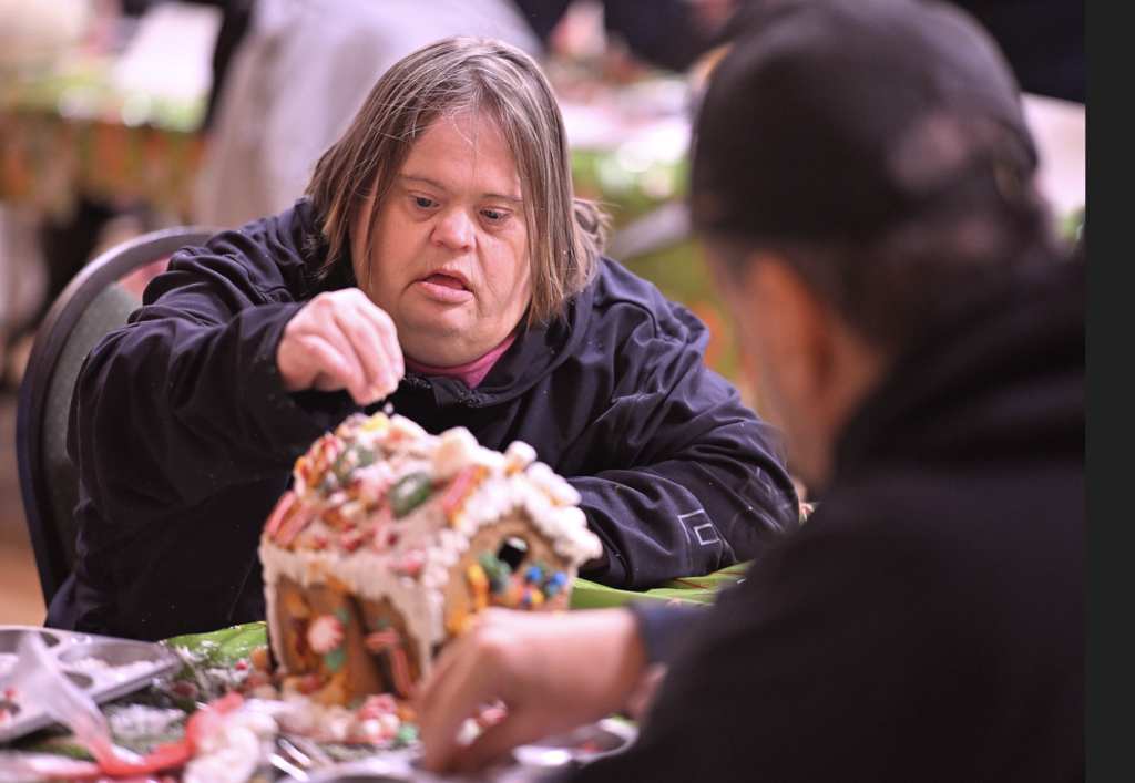 woman decorating a gingerbread houes