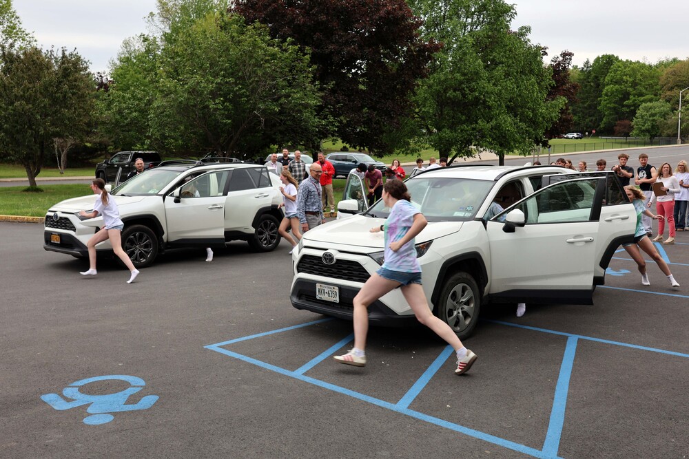 students running around cars in Battle of the Belts