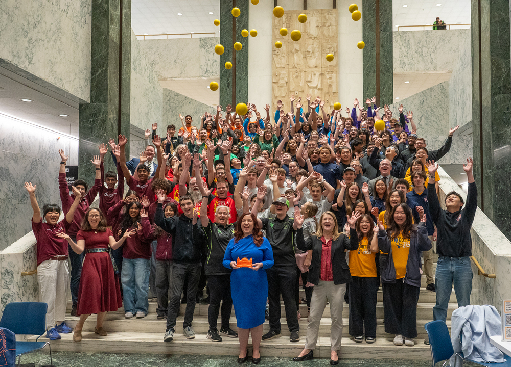 students and lawmakers tossing balls into air on assembly steps