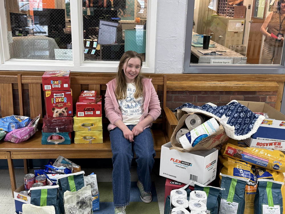 girl posing with stacks of pet items she donated!