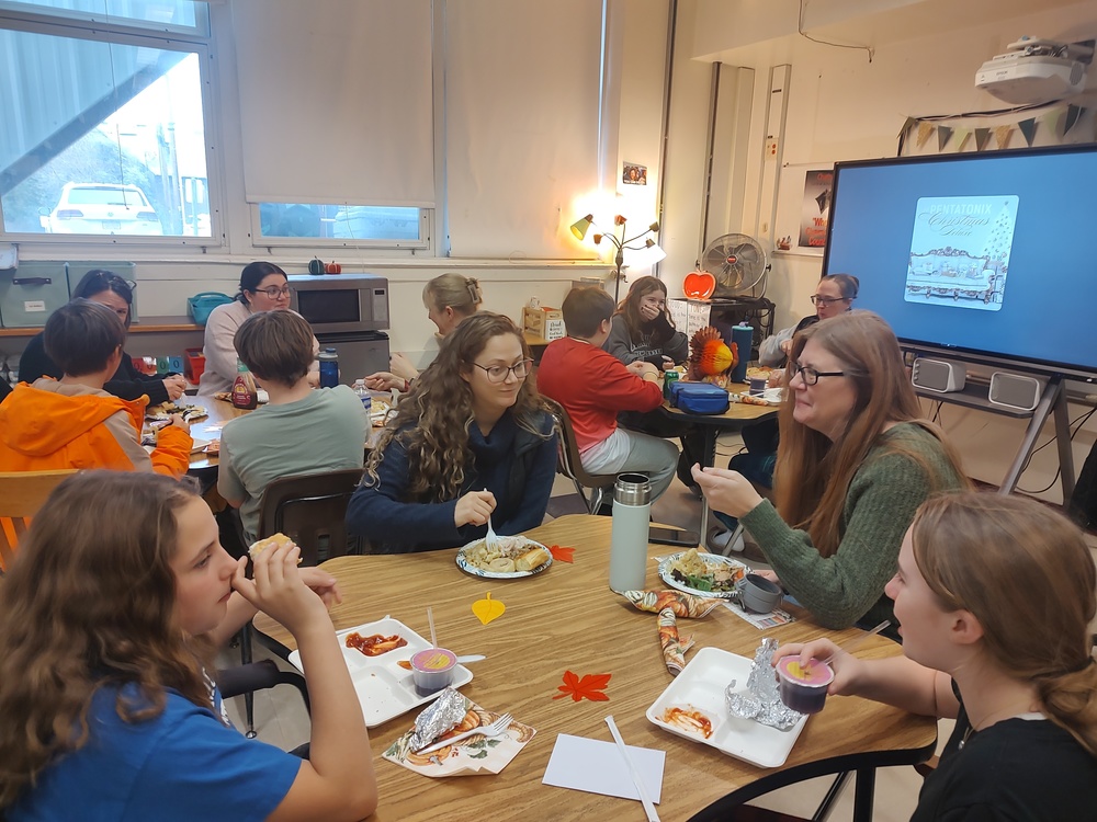 students and teachers eating Thanksgiving meal in classroom.
