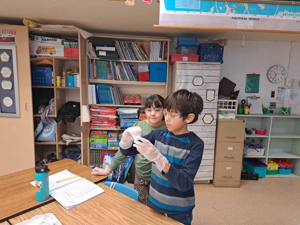 students looking at substance in cup