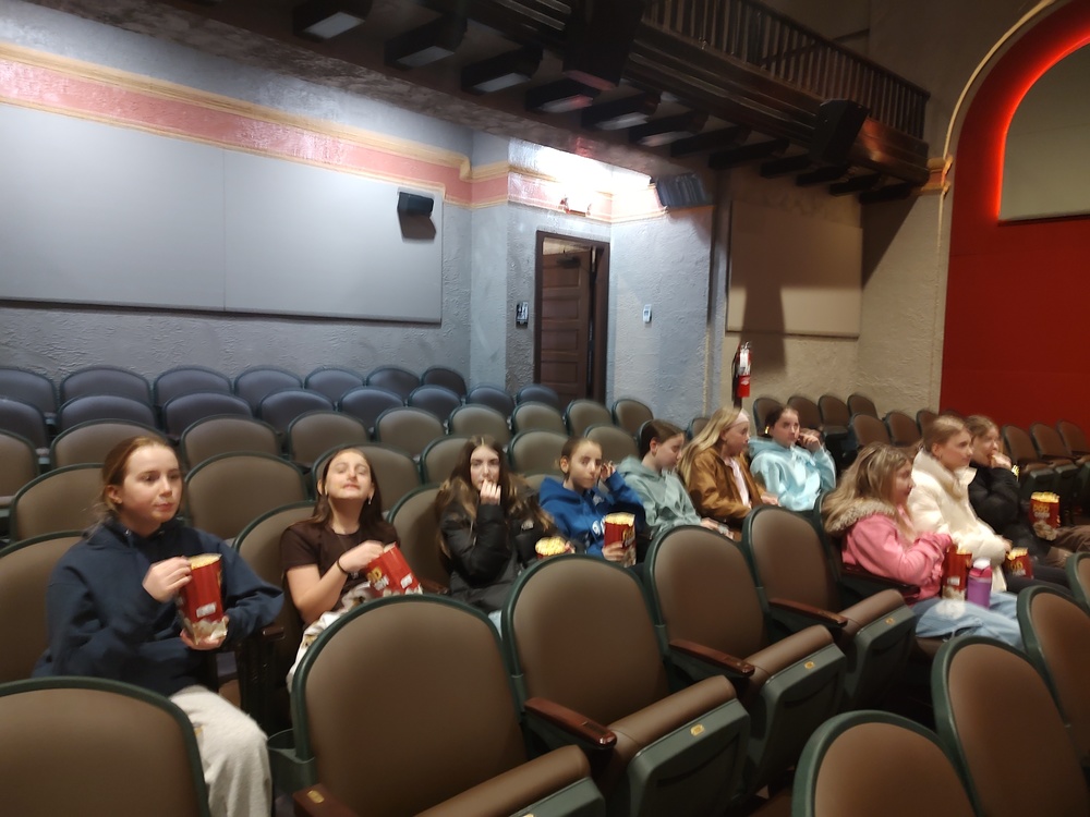 girl eating popcorn in movie theater seats.