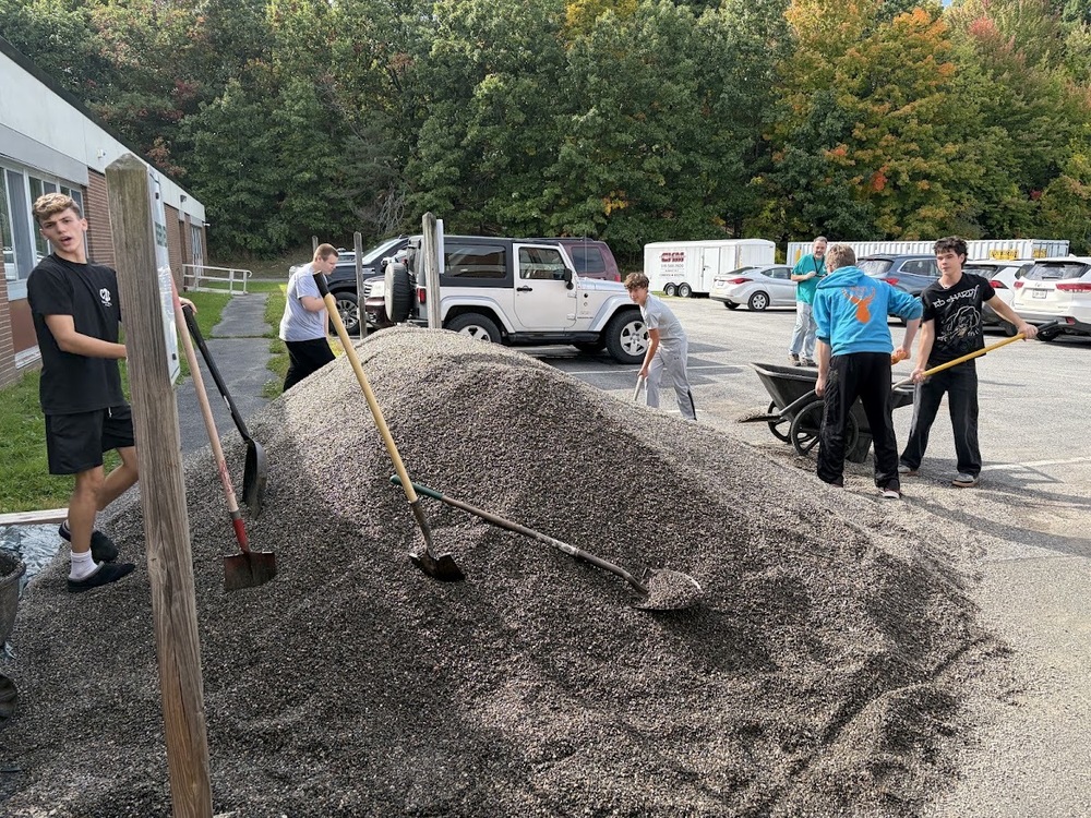 students moving big pile of peastone