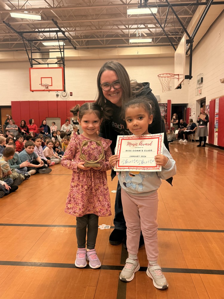 two girls and teacher pose with golden tamborine award