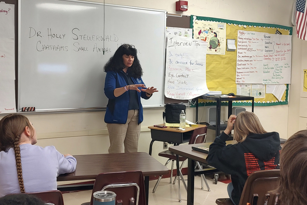 woman speaking in front of middle school students