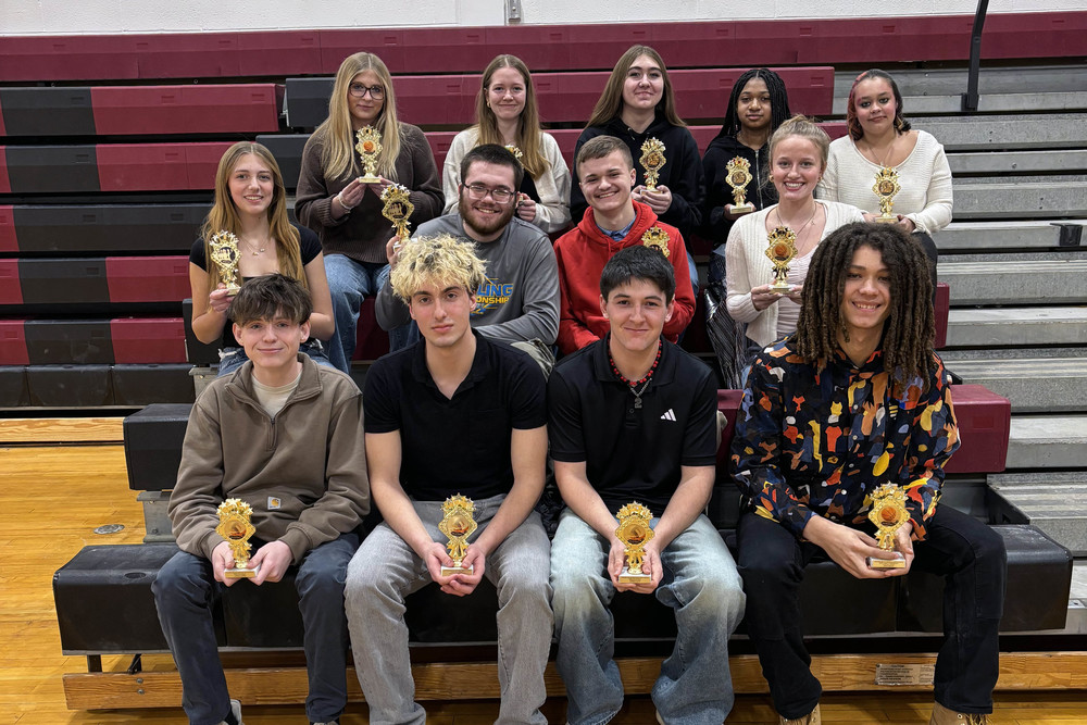 Winter sports awardees sitting on bleachers with trophies