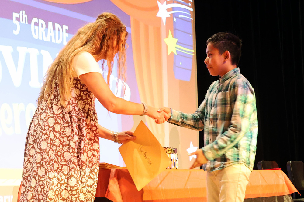 woman shaing young boy's hand and handing him a certificate