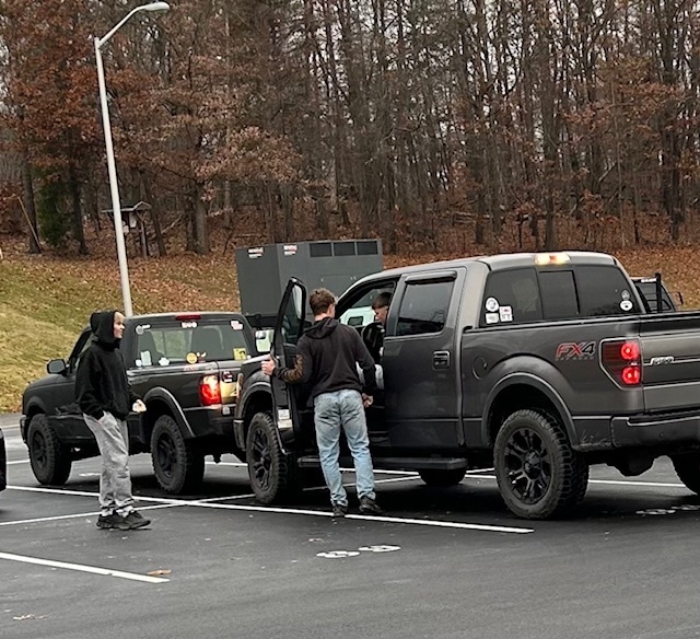 two teenage boys checking seatbelt of teenage boy in pickup truck