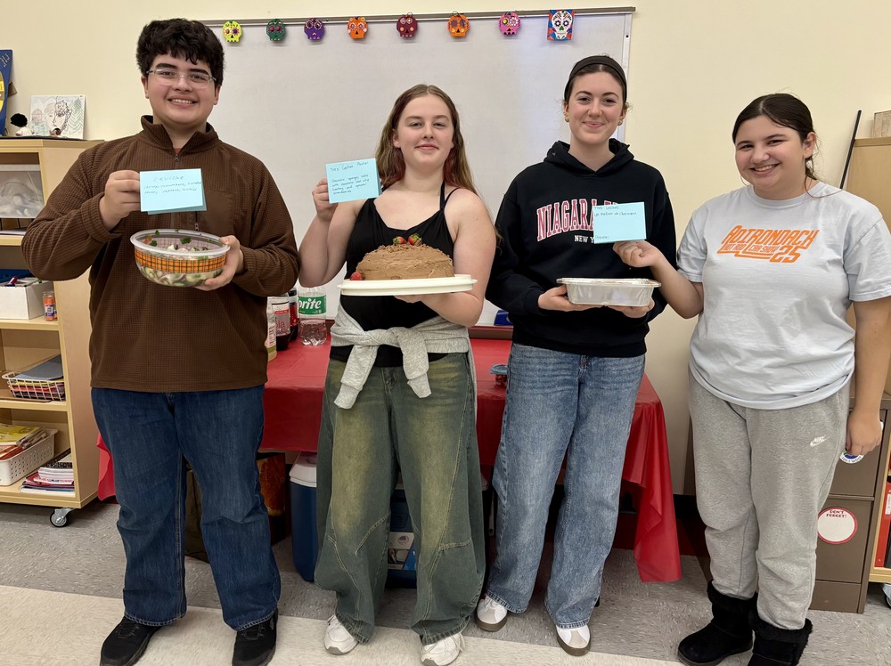 students holding up dishses of food and cards describing them 