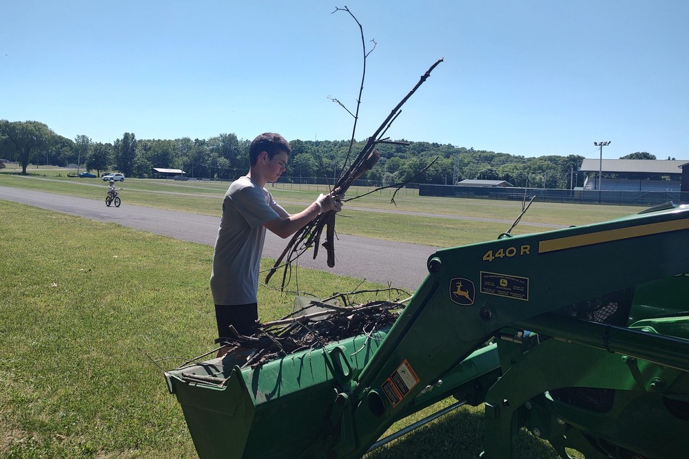 boy loading sticks into bucket loader