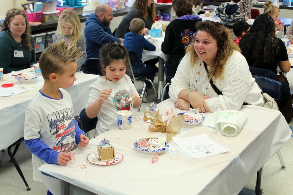 woman, boy and girl making gingerbread houses at table