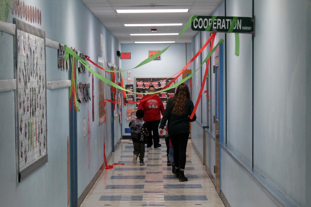 students and teachers walking in hallway strewn with holiday ribbons