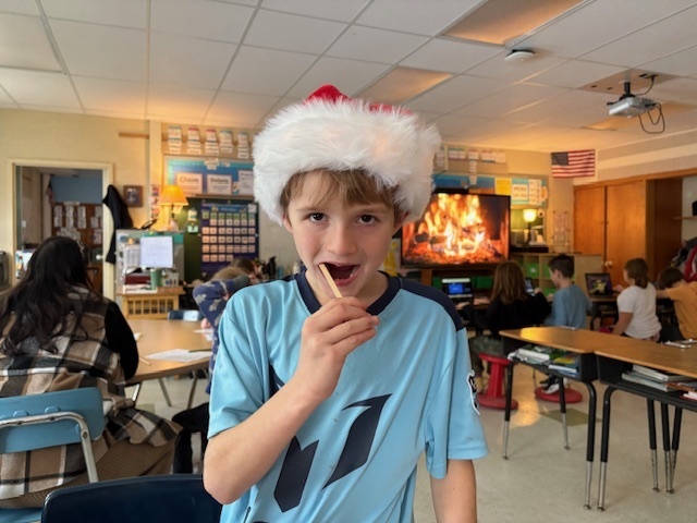 student in Santa hat harvesting cheek cells from his mouth with popsicle stick