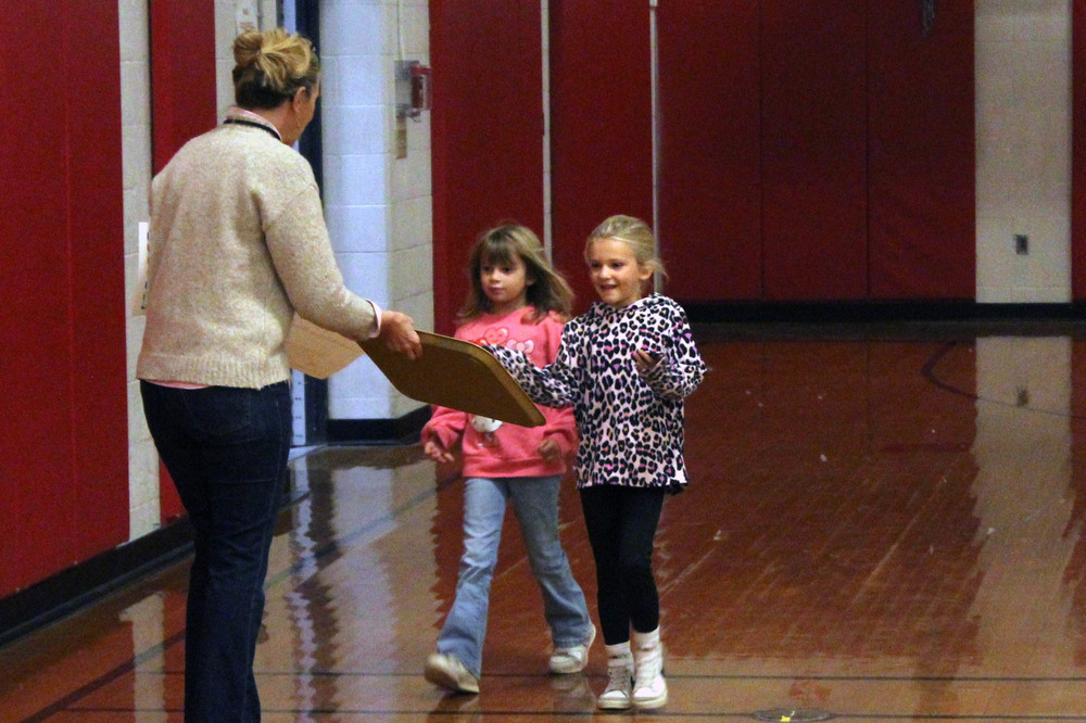 girls getting gold colored tray from woman
