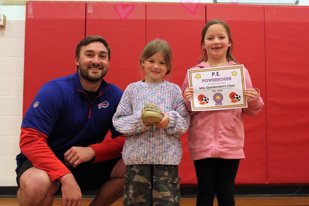 two girls and man pose with golden sneaker award