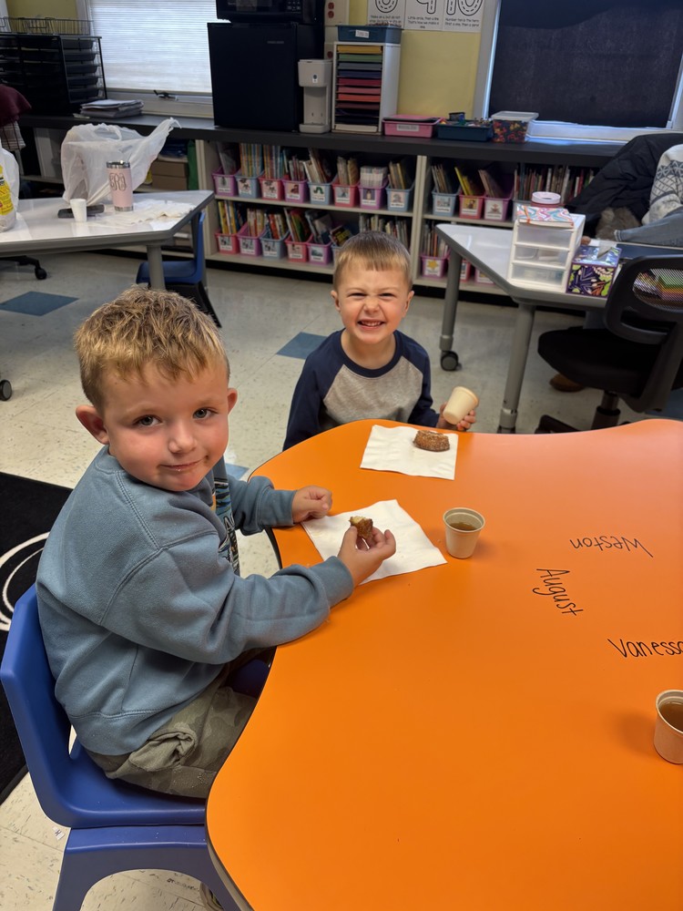 boys seated at table eating cider donuts