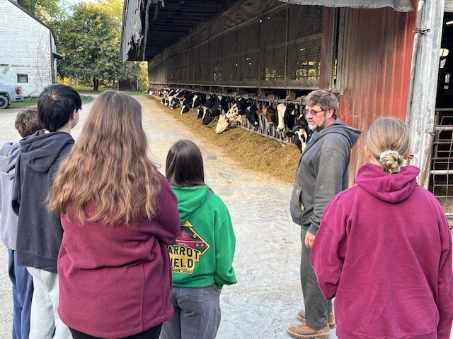 student being whown dairy barn by farmer