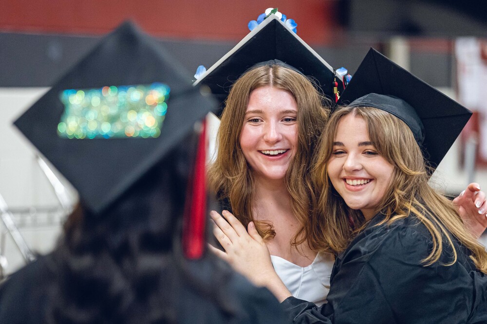 two girls in graduation caps and gowns smiling