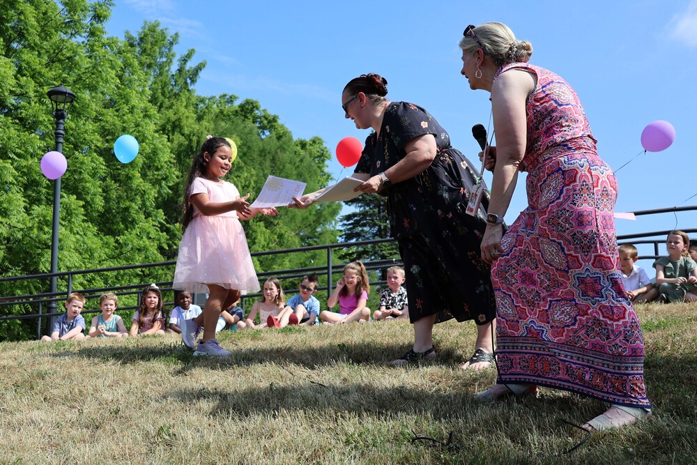 woman handing young girl a certificate