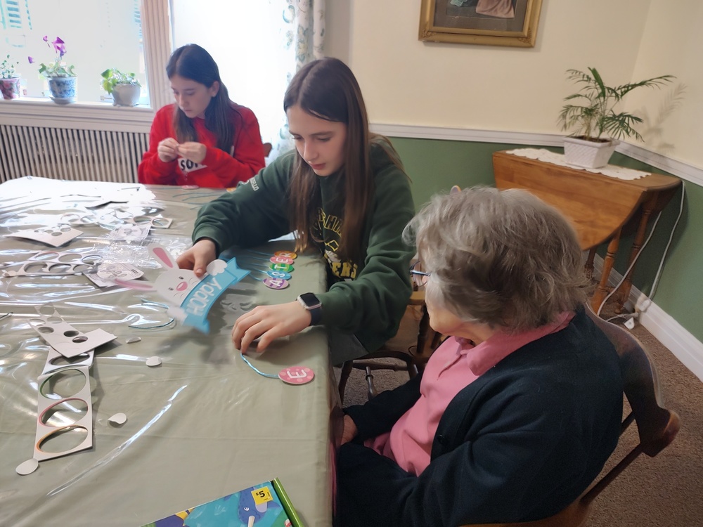two girls making crafts with senior woman